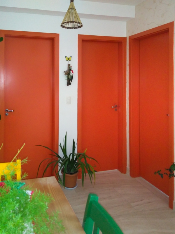 Sala com parede branca e portas em tom de vermelho na cor Terra Exótica Suvinil | Foto de Lufe Gomes