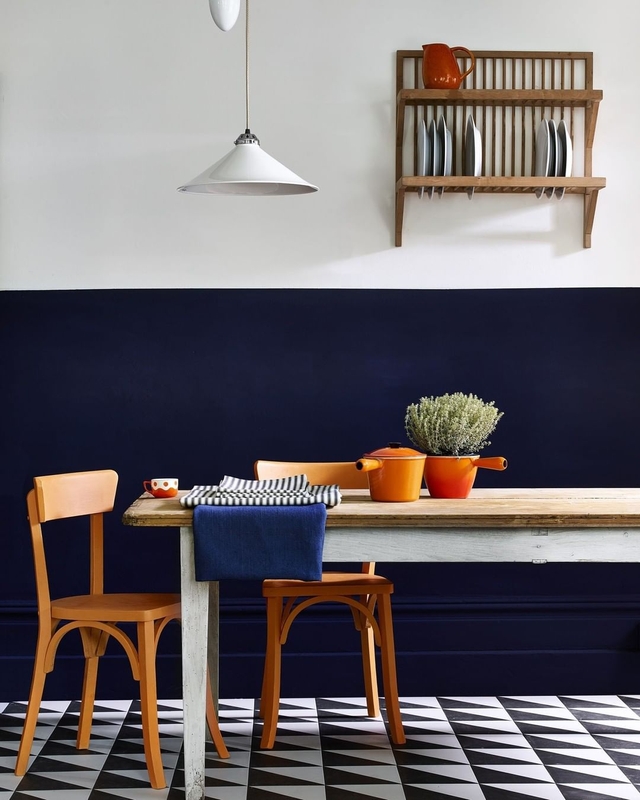Cozinha com mesa de madeira clara, meia parede na cor Luau Suvinil e superior branca. Objetos de decoração destacados.