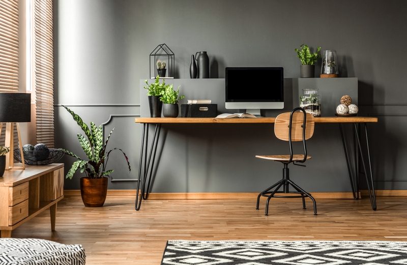 Home office com escrivaninha, cadeira em madeira, objetos de decoração em preto e parede na cor Rua das Pedras Suvinil.