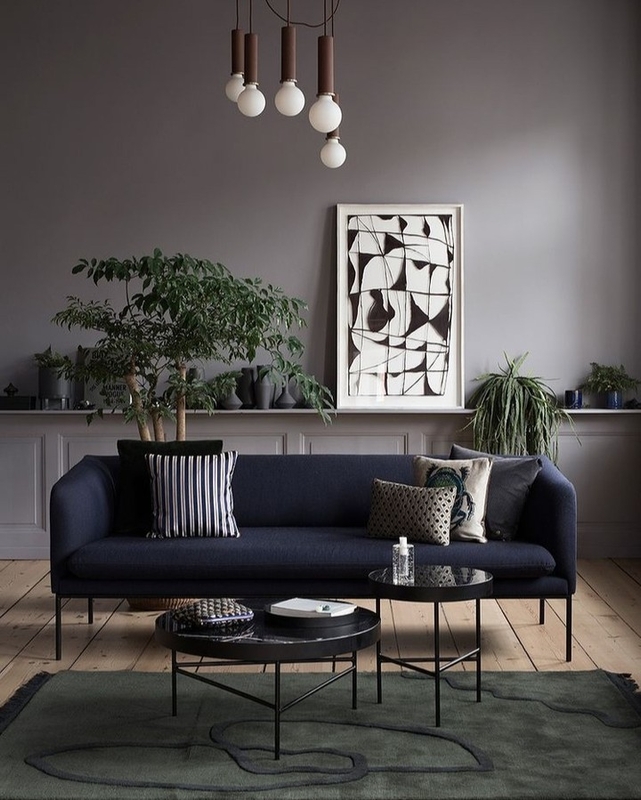 Sala de estar com sofá e mesa de centro pretos, objetos de decoração e paredes pintadas em cinza claro, cor Brasão Suvinil.