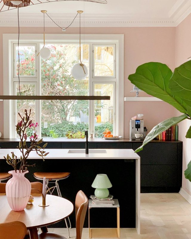 Janela branca em destaque na cozinha com uma ilha e balcões pretos com tampo branco | Parede na cor Mimosa Suvinil