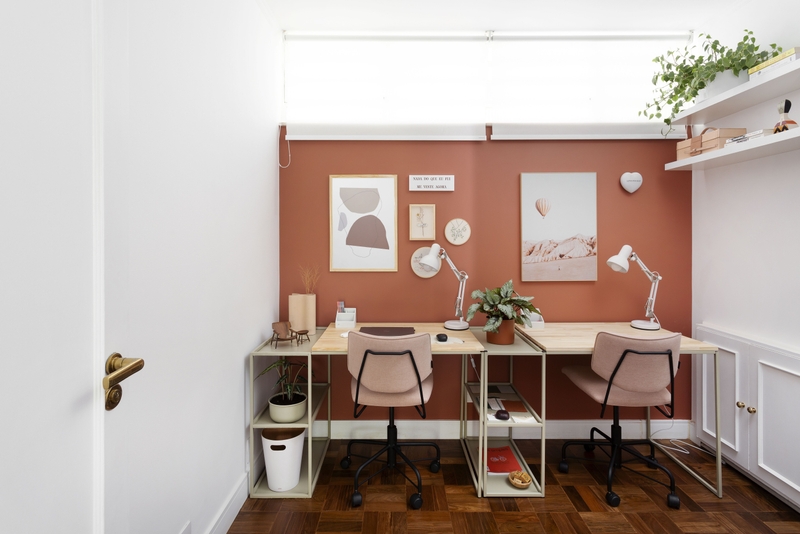 Home office com visual destacado pela parede na cor Tamarindo Suvinil, mesa de madeira, plantas e cadeira de escritório rosa