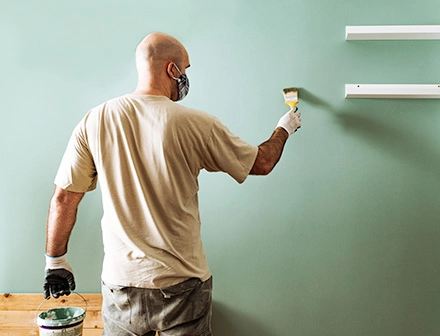 Homem pintando parede verde.