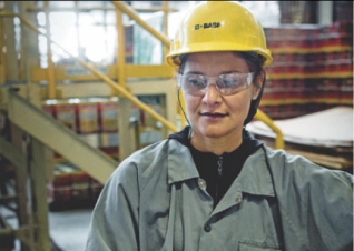 Colaboradora com capacete e óculos de proteção (EPI) em uma fábrica da Suvinil.