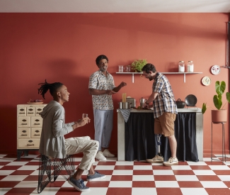 Três homens confraternizando em uma cozinha.