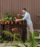 Homem cuidando de plantas em área externa de sua casa, simbolizando o compromisso da Suvinil com a sustentabilidade.